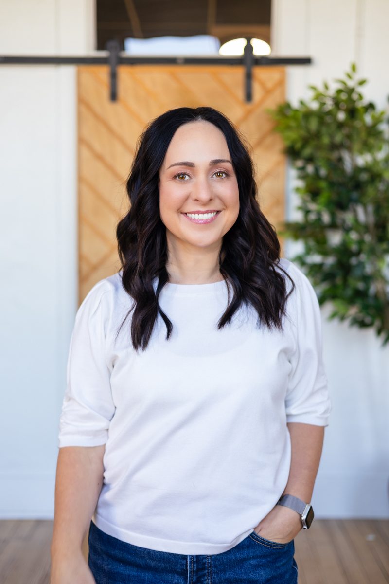 Sara Stockinger standing in front of a wooden barn door